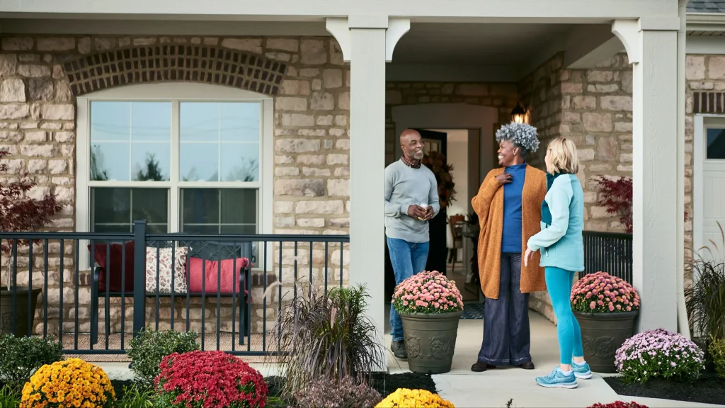 Three neighbors chatting on a front porch